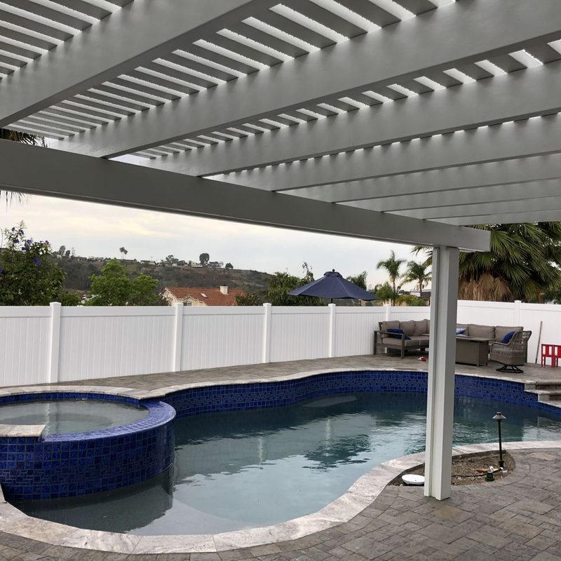 White vinyl fence and patio cover surrounding a swimming pool and spa