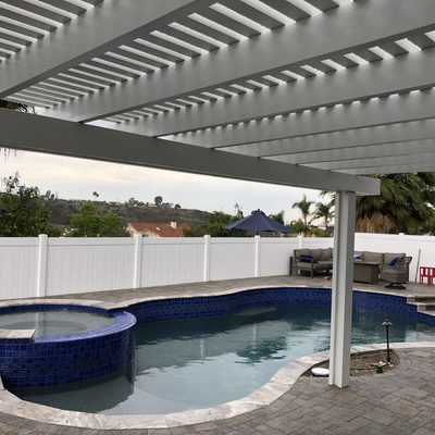 White vinyl fence and patio cover surrounding a swimming pool and spa