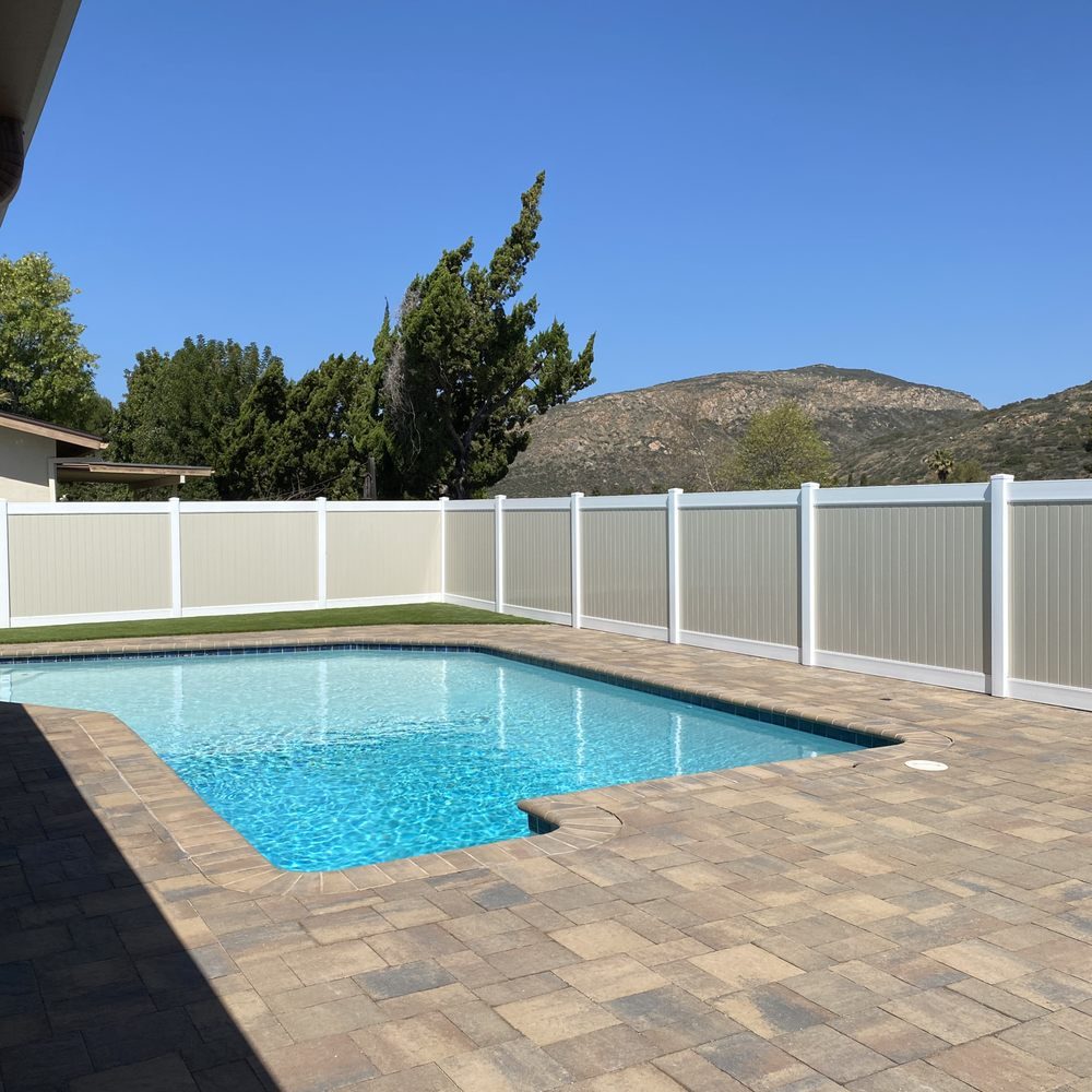 White vinyl privacy fence enclosing a backyard pool with the East County hills behind it, built by Apache Fence