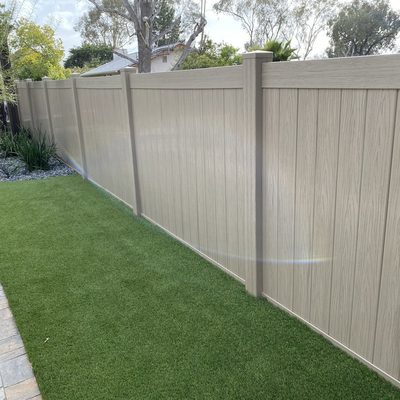 Tan vinyl privacy fence enclosing a yard with artificial turf