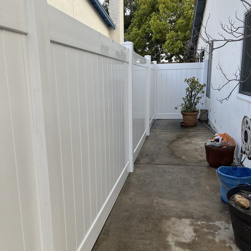 White vinyl privacy fence dividing two neighboring yards