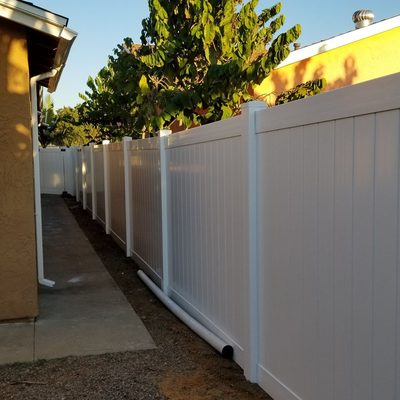 White vinyl fence lining a narrow walkway beside a home