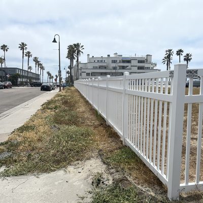 Long run of white vinyl fence with picket top along a coastal street