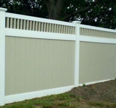 White vinyl privacy fence around an open lot with clear sky above