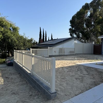 White vinyl fence with picket top running the length of a ranch style home